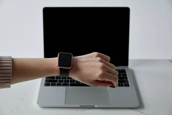 Частковий вигляд жінки в смарт-годиннику і ноутбуці з порожнім екраном ізольовано на сірому — стокове фото