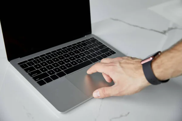 Partial view of man in smart watch using laptop on white marble surface — Stock Photo