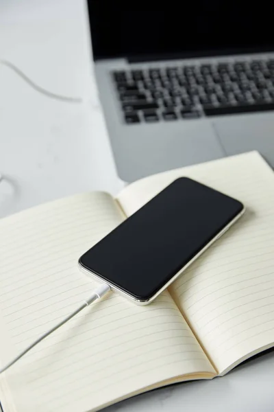 Selective focus of smartphone with blank screen, notebook and laptop on white surface — Stock Photo
