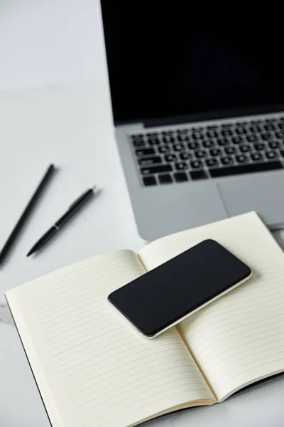 Foyer sélectif du smartphone avec écran blanc, portable et ordinateur portable sur la surface blanche — Photo de stock