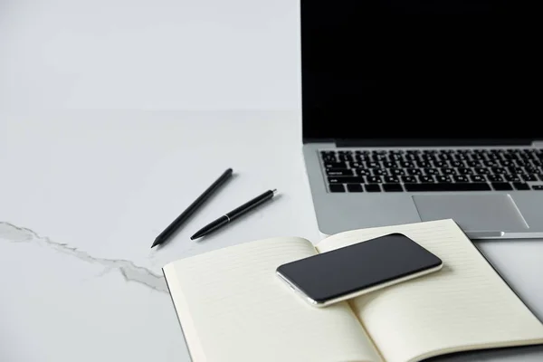 Selective focus of smartphone on notebook, and laptop with blank screen isolated on grey — Stock Photo