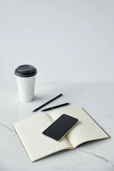 Smartphone with blank screen, notebook and disposable cup isolated on grey — Stock Photo