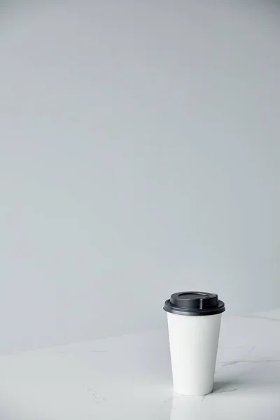 Tasse jetable blanche avec capuchon noir isolé sur gris avec espace de copie — Photo de stock