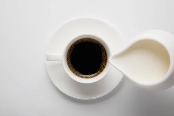 Top view of coffee cup and jug of milk on white — Stock Photo
