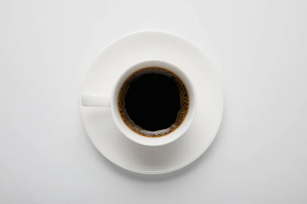 Vista superior de la taza de café negro y platillo en blanco - foto de stock