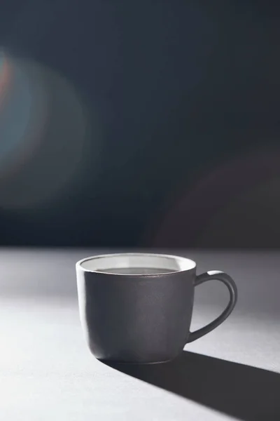Cup of coffee on grey surface on black — Stock Photo
