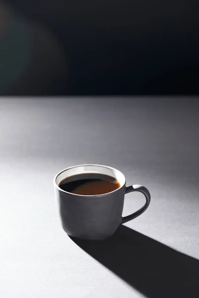 Cup of coffee on grey surface on black — Stock Photo