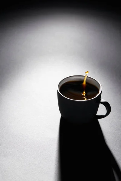 Cup full of coffee with drop on dark textured surface — Stock Photo