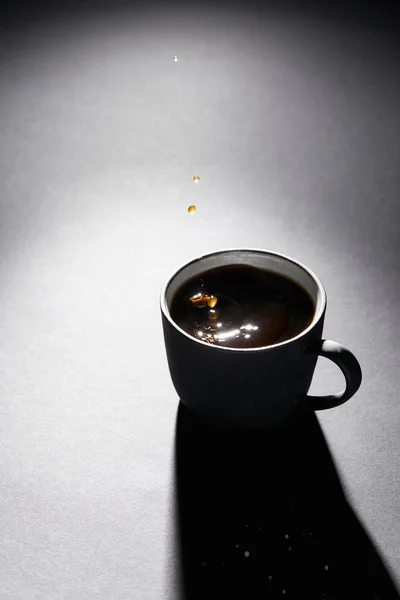 Cup full of coffee with drops on dark textured surface — Stock Photo