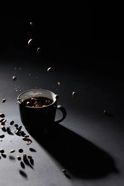Xícara de café e grãos de café na superfície texturizada escura — Fotografia de Stock