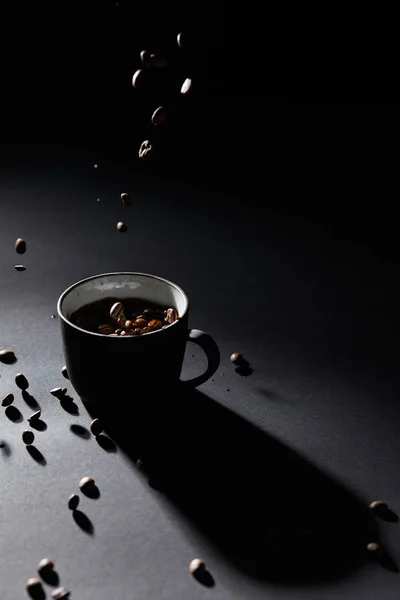 Tasse à café et grains de café sur surface texturée sombre — Photo de stock