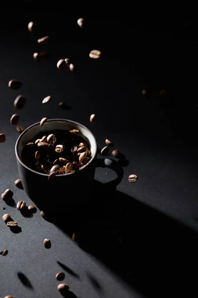 Tasse à café et grains de café sur surface texturée sombre — Photo de stock