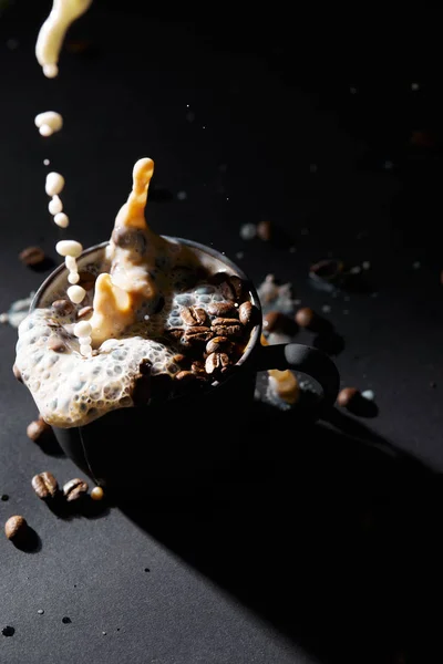 Taza de café con granos de café y verter la leche en la superficie oscura - foto de stock