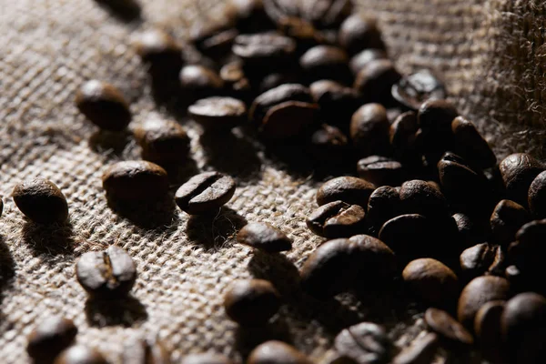 Enfoque selectivo de granos de café tostados en la textura del saco - foto de stock