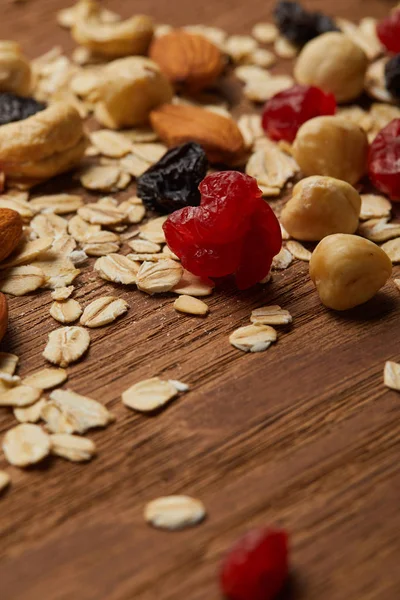 Close up of oat flakes with dried berries and hazelnuts on wooden table — Stock Photo