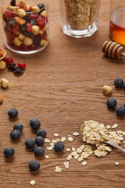 Enfoque selectivo de copos de avena, frutos secos y bayas secas en mesa de madera con espacio de copia - foto de stock