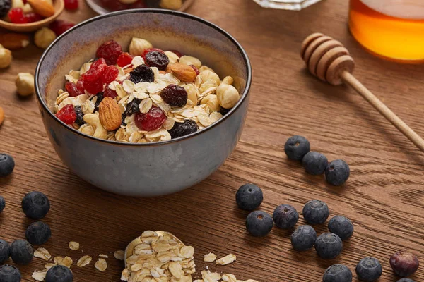 Müsli in Schüssel mit Nüssen und getrockneten Beeren zum Frühstück auf Holztisch zubereitet — Stockfoto