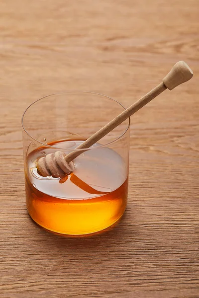 Miel biologique visqueux en verre avec bâton sur table en bois — Photo de stock