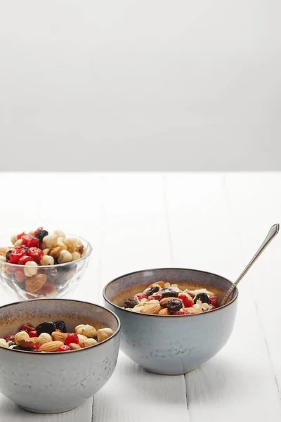 Taças com muesli, bagas secas e nozes servidas ao pequeno-almoço isolado em cinzento — Fotografia de Stock