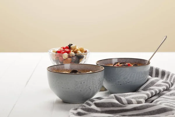 Bowls with muesli, dried berries and nuts served for breakfast isolated on beige — Stock Photo