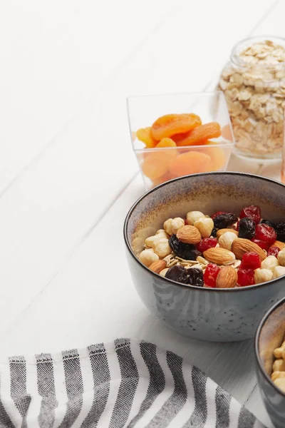 Миски с мюсли, сушеные ягоды и орехи подаются на завтрак с сушеными абрикосами на белом деревянном столе с копировальным местом — стоковое фото