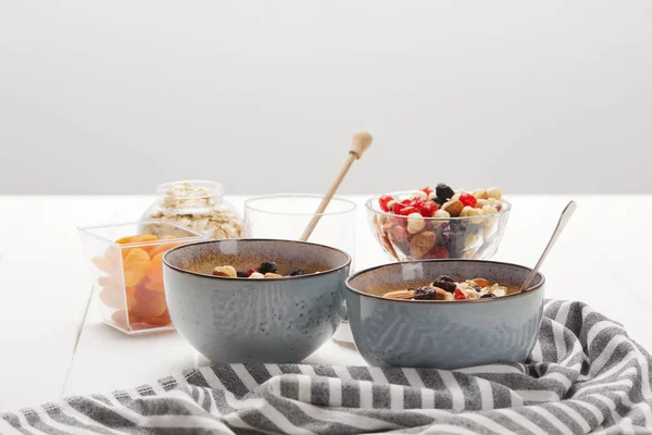 Tazones con muesli, bayas secas y frutos secos servidos para el desayuno con albaricoques secos aislados en gris - foto de stock