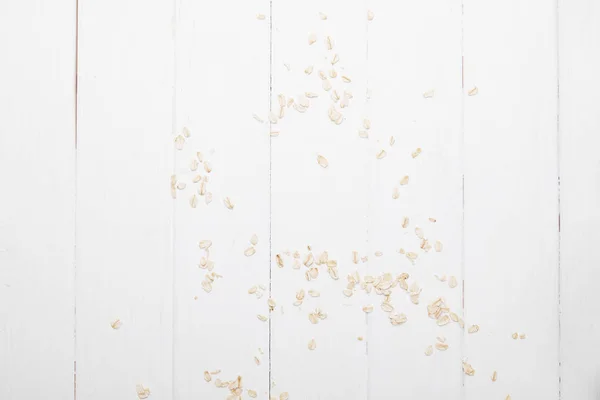 Top view of scattered oat flakes on white wooden table — Stock Photo