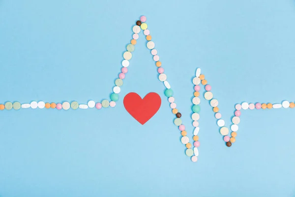 Flat lay with colorful pills and paper heart on blue — Stock Photo