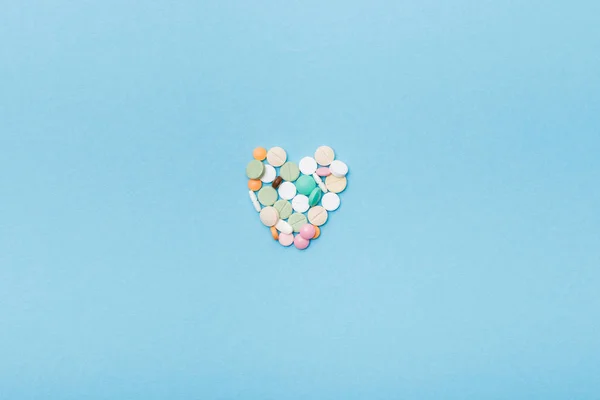 Flat lay with colorful pills on blue surface — Stock Photo