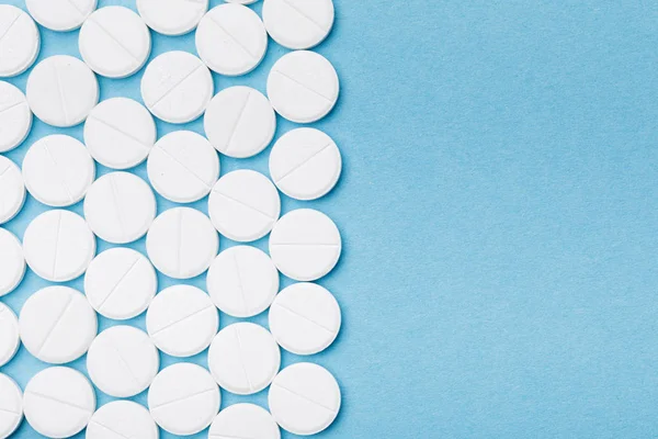 Vista dall'alto di pillole bianche sulla superficie blu — Foto stock