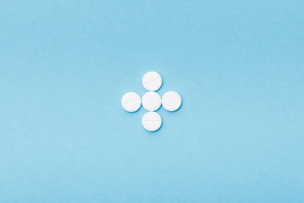 Плоский лежал с белыми таблетками на голубой поверхности — стоковое фото