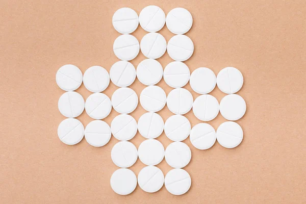 Flat lay with white pills on brown surface — Stock Photo