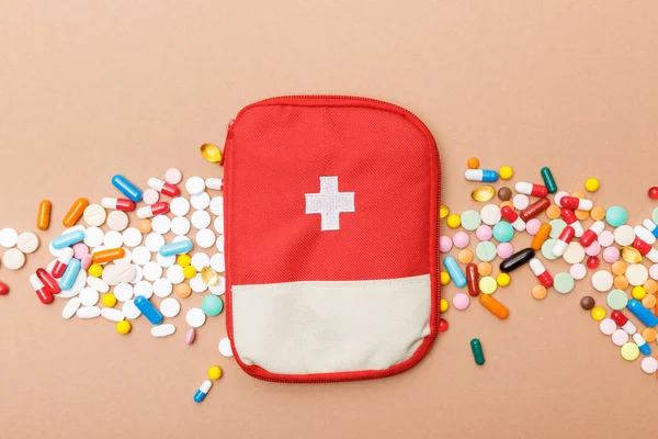 Vue du dessus du sac de trousse de premiers soins et des pilules colorées sur la surface brune — Photo de stock