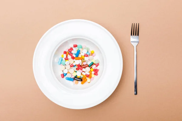 Top view of bowl with pills and fork on brown surface — Stock Photo