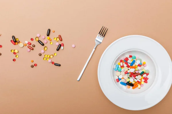 Top view of bowl with pills and fork on brown surface — Stock Photo