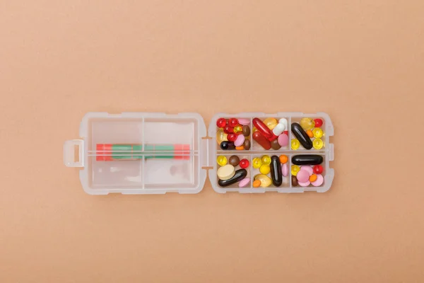 Top view of container with colorful pills on brown surface — Stock Photo