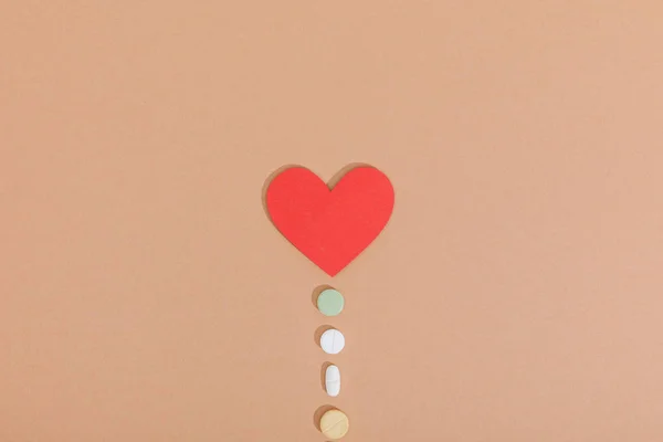Vista superior del corazón de papel y pastillas en la superficie marrón - foto de stock
