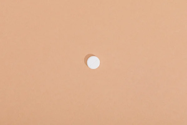 Top view of white pill on brown surface — Stock Photo