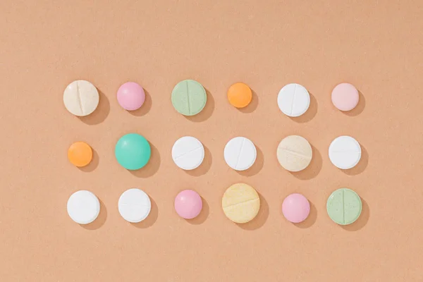 Pose plate avec des pilules colorées sur la surface brune — Photo de stock