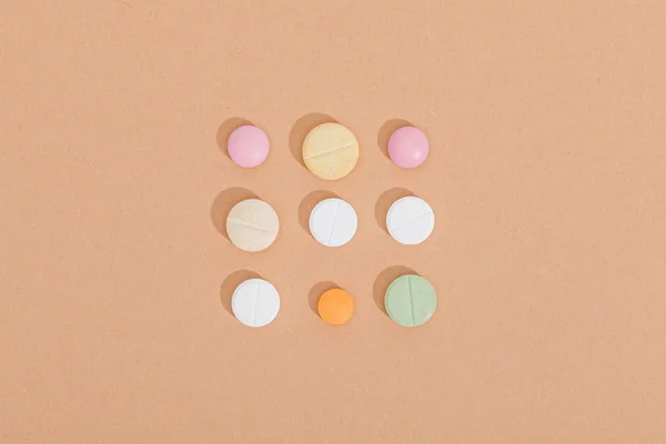 Flat lay with colorful pills on brown surface — Stock Photo