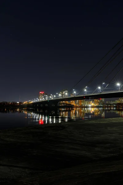 Paesaggio urbano con edifici illuminati, ponte e fiume al nigth — Foto stock