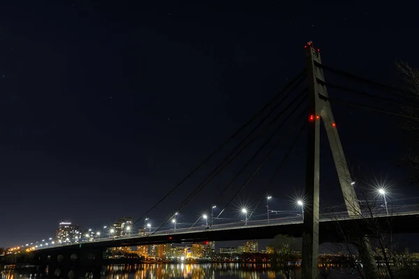 Темный городской пейзаж с освещенными зданиями и мостом — стоковое фото