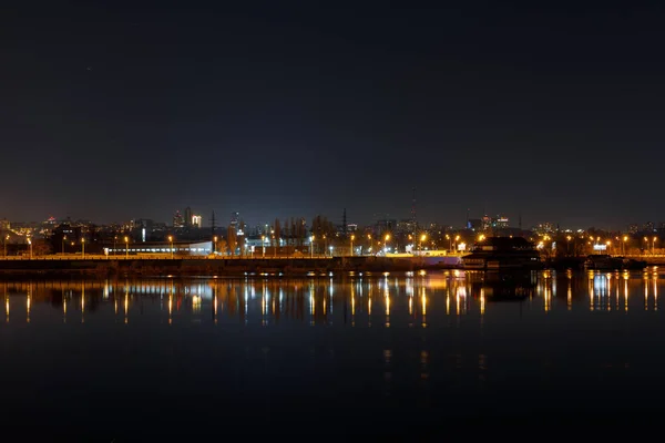 Paysage urbain sombre avec bâtiments éclairés et rivière calme au nigth — Photo de stock