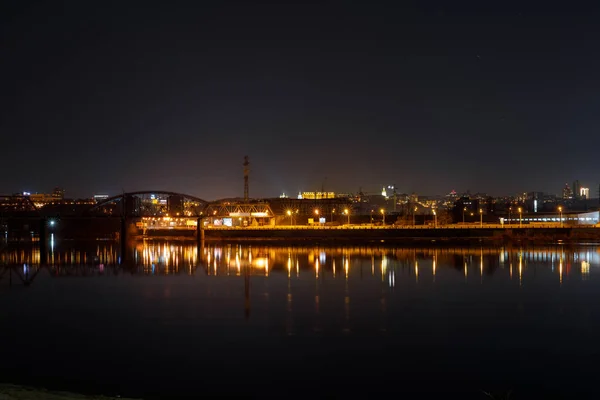 Paysage urbain sombre avec rivière et bâtiments éclairés sur le rivage la nuit — Photo de stock