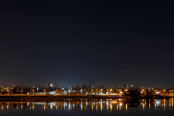 Paesaggio urbano buio con edifici, luci e fiume di notte — Foto stock