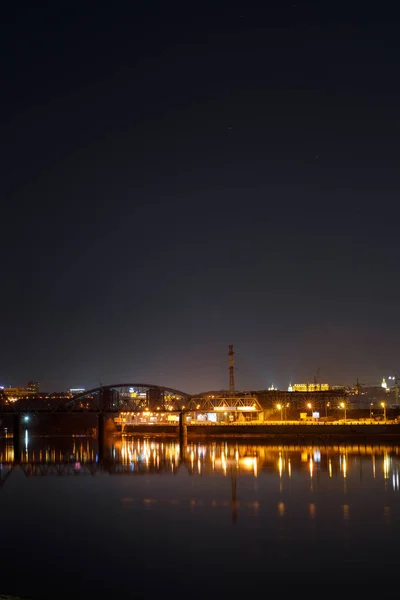 Dunkles Stadtbild mit Gebäuden, Lichtern, Fluss und Nachthimmel — Stockfoto