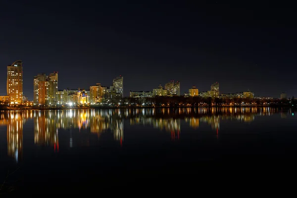 Picturesque dark cityscape with illuminated buildings, river and night sky — Stock Photo