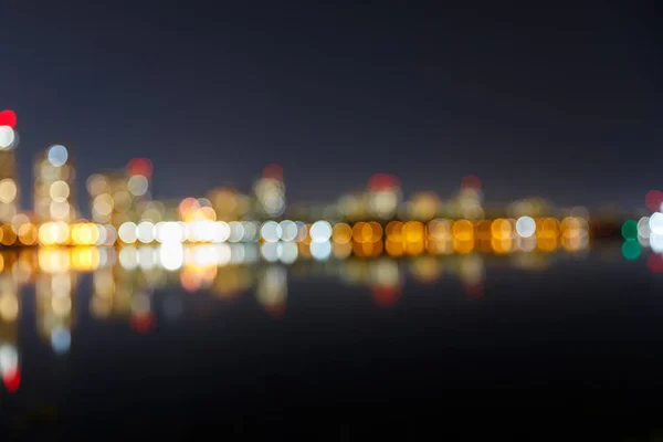 Verschwommenes dunkles Stadtbild mit beleuchteten Gebäuden und Spiegelungen — Stockfoto