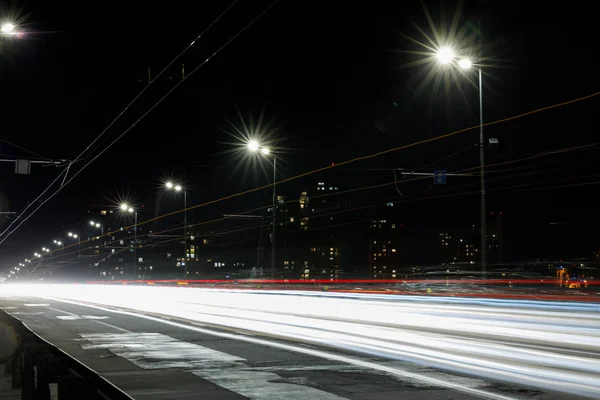 Longue exposition des lumières sur la route la nuit près des bâtiments — Photo de stock