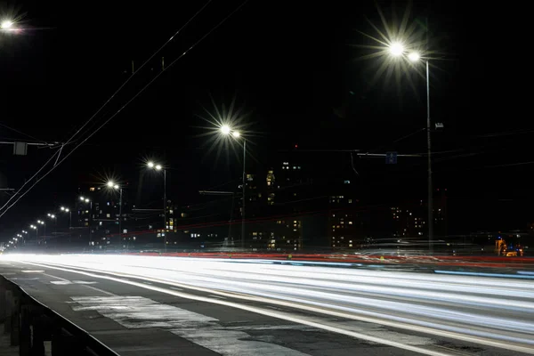 Longa exposição de luzes na estrada à noite perto de edifícios — Fotografia de Stock